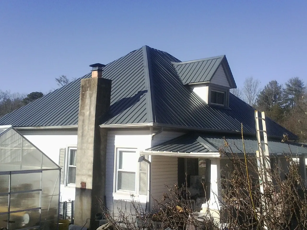 Dark blue standing seam metal roof on a white farmhouse with dormer — Slate & Tile Roof Repair by Roofing Brothers in El Granada