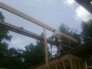 Carpenter setting a ridge beam over a new addition frame — Ice Dam Removal by Roofing Brothers in El Granada