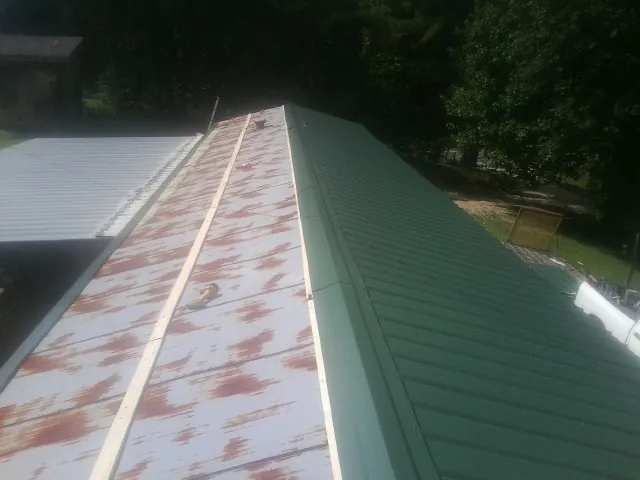 Old rusted panels beside newly installed green metal roofing — Wind Damage Roof Repair by Roofing Brothers in El Granada