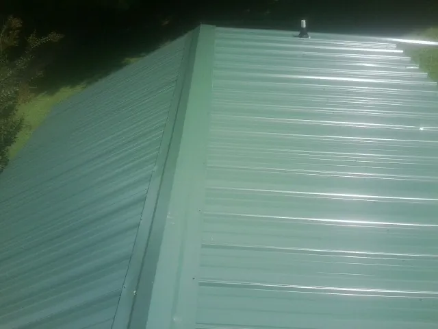 New green metal panels meeting at the ridge of a roof — Flat Roof Repair work by our crew in El Granada
