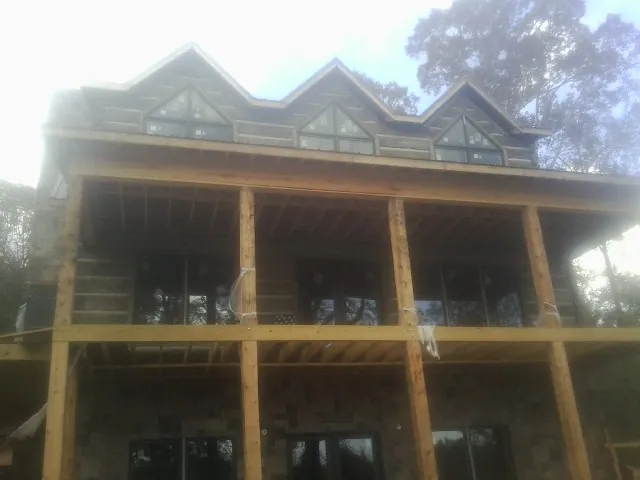 Dormers and porch framing on a large log home under construction — Roof Coating work by our crew in El Granada