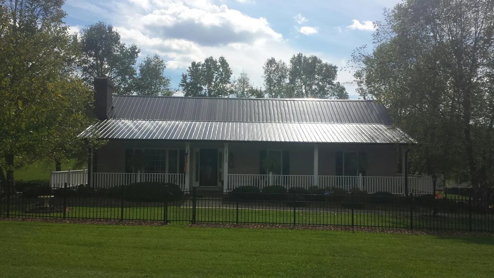 Gray metal roof on a brick ranch with a full width front porch — Gutter Guard Installation work by our crew in El Granada