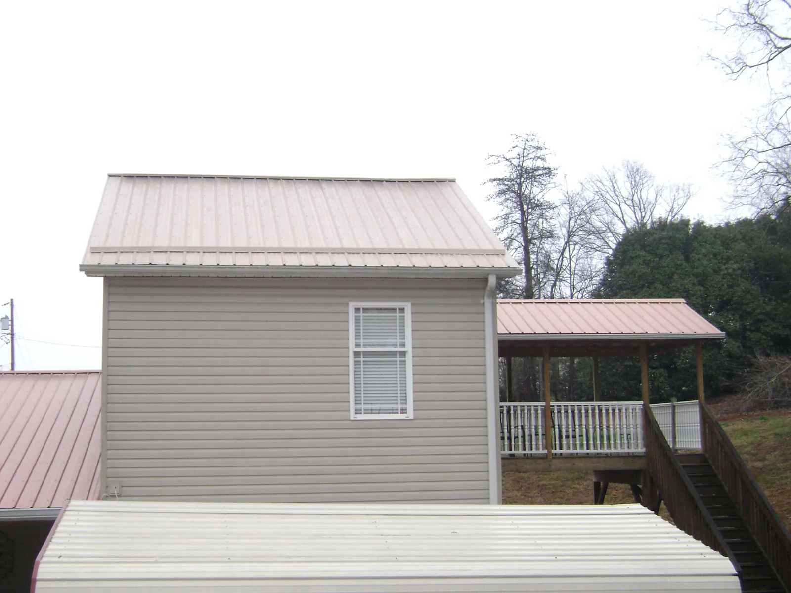 Tan metal roofs on a two story addition and attached porch, from a Roof Replacement job in El Granada