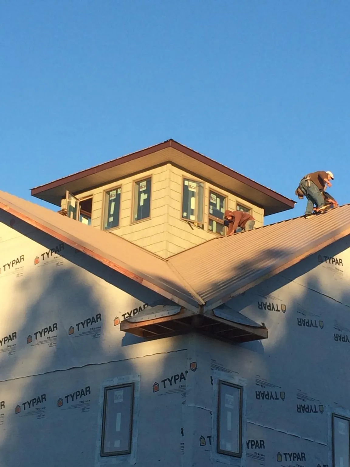 Roofers working around a rooftop cupola on a new metal roof at sunset — Roof Waterproofing in El Granada by Roofing Brothers
